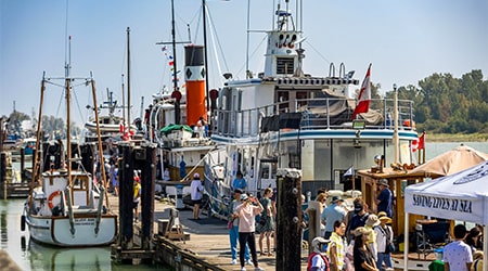 People viewing several boats along a dock in Steveston Harbour