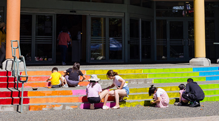 Group of youth painting the Pride stairs outside the Richmond Cultural Centre