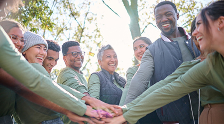 Group of people in a circle with hands in the centre