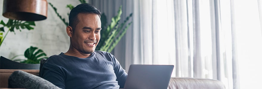 Man sitting on a couch and reading a laptop