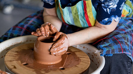 Close-up of person forming a clay vessel on a potter's wheel