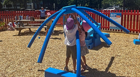Kids building with big blue blocks in a playground