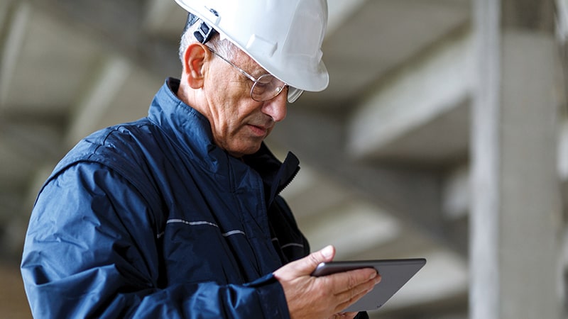 Man in a hard hat looking at a tablet device