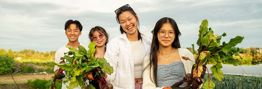 View of four youth holding fresh produce and smiling