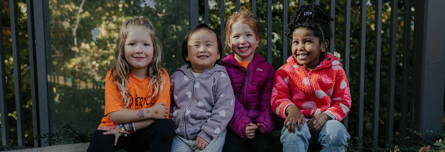 Four young children posting against a fence