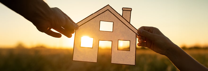 Two hands  holding a paper home in sunset