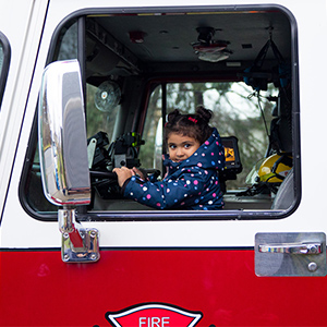 Little girl sitting in the driver's seat of a firetruck