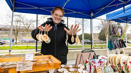 A vendor holding up their wares at Carols and Crafts