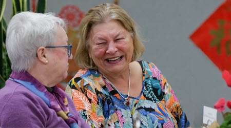 A pair of seniors laughing and enjoying a program