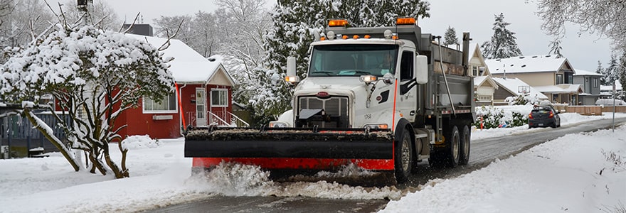 Snow plow clearing snow from a residential city street