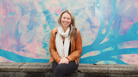 Artist Desirée Patterson sitting in front of the new public artwork, Visions of Biophilia