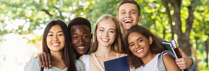Five young people posing for a photo in a park